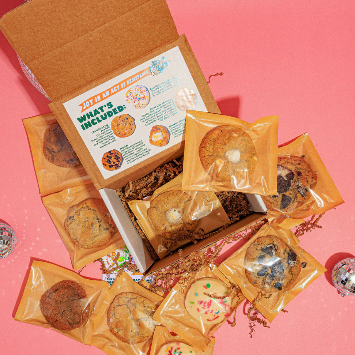 Box of cookies with some cookies outside the box on a pink background