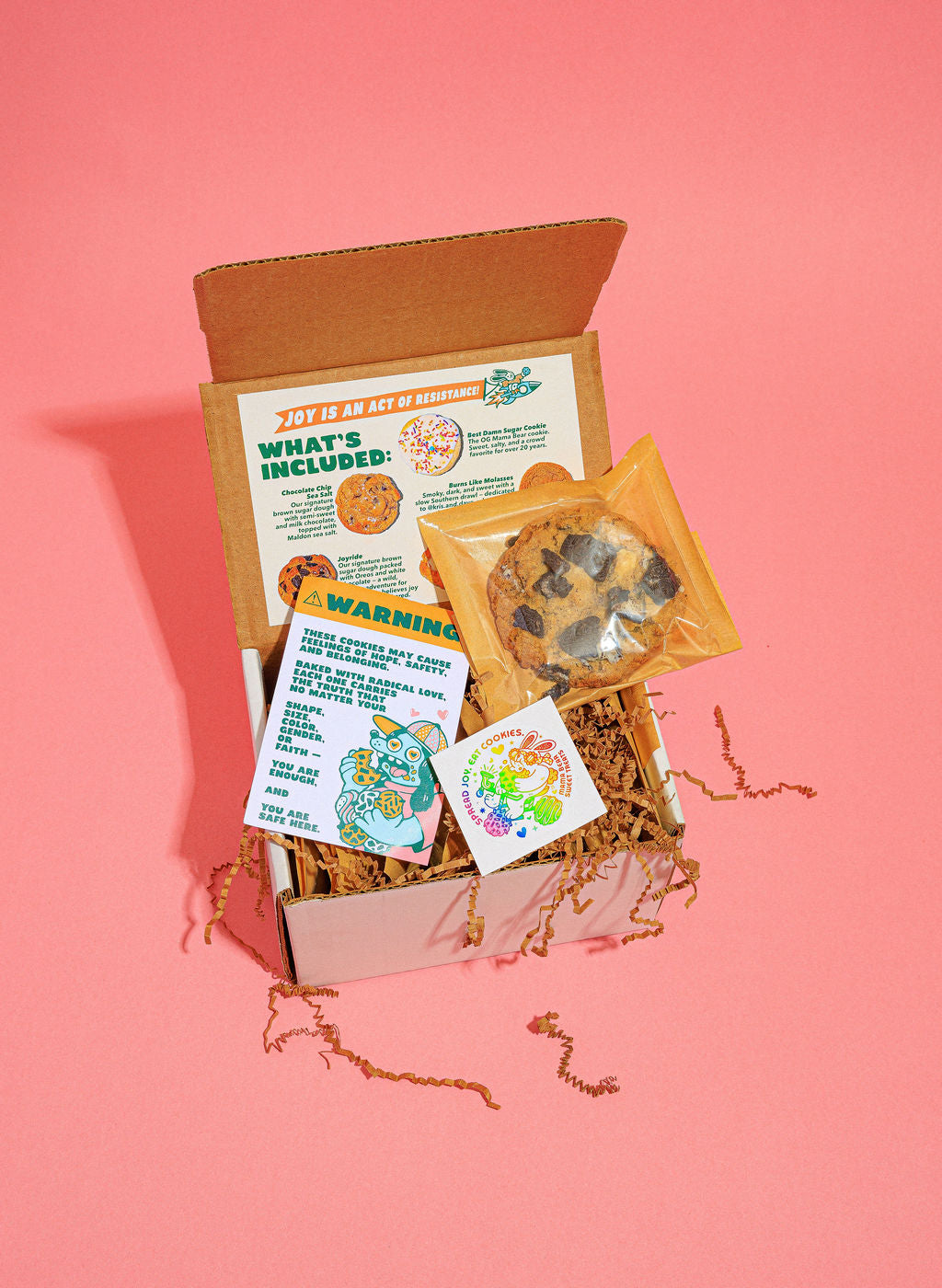 Open box with cookies and colorful labels on a pink background