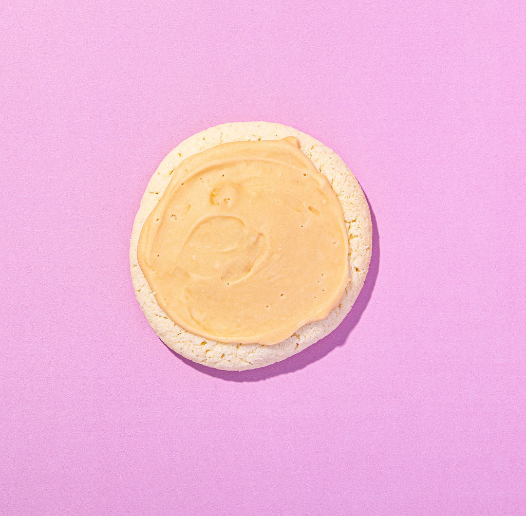 Round cookie with a yellow icing on a pink background